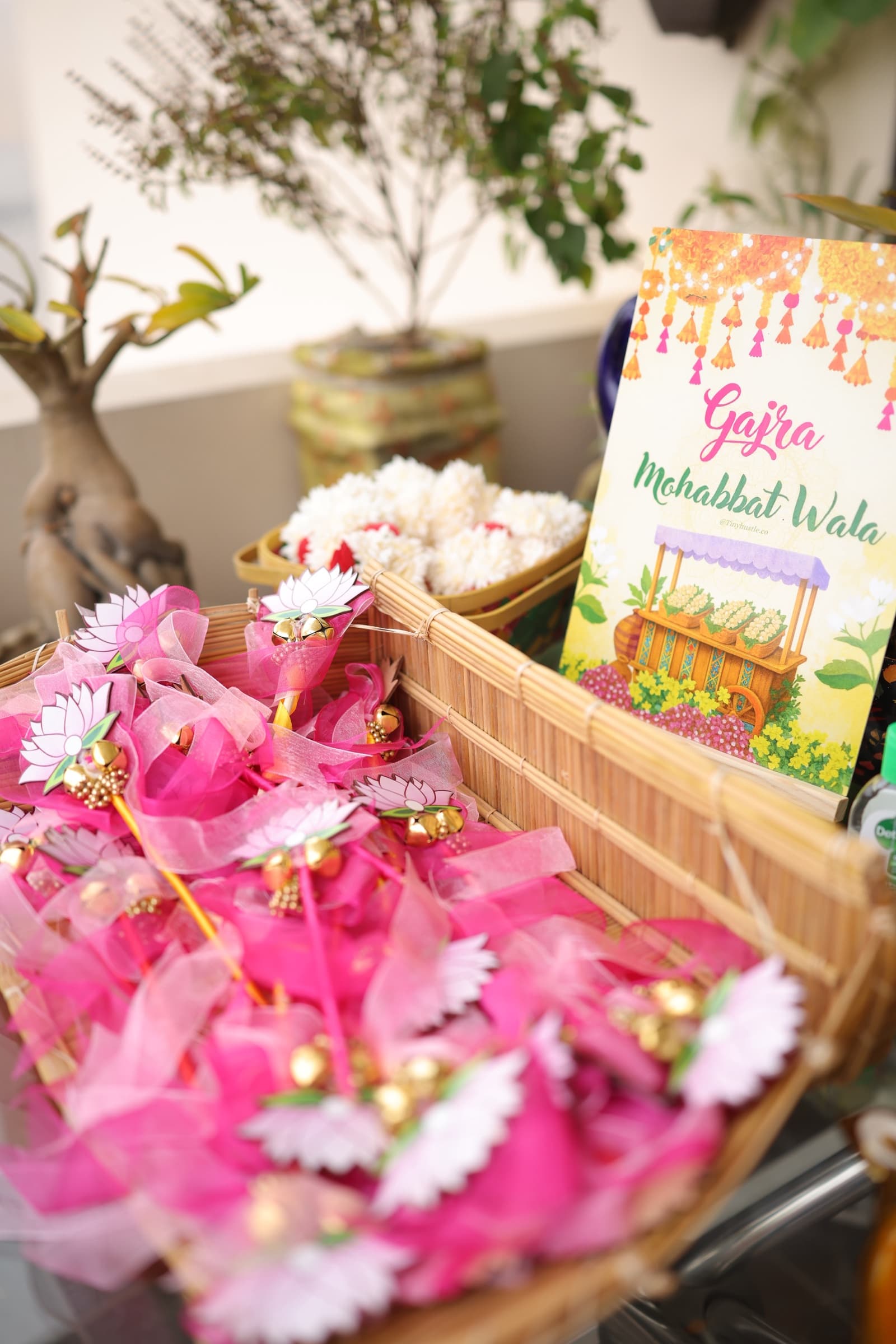 Pink pinwheel favours and a haldi welcome card on a bamboo tray
