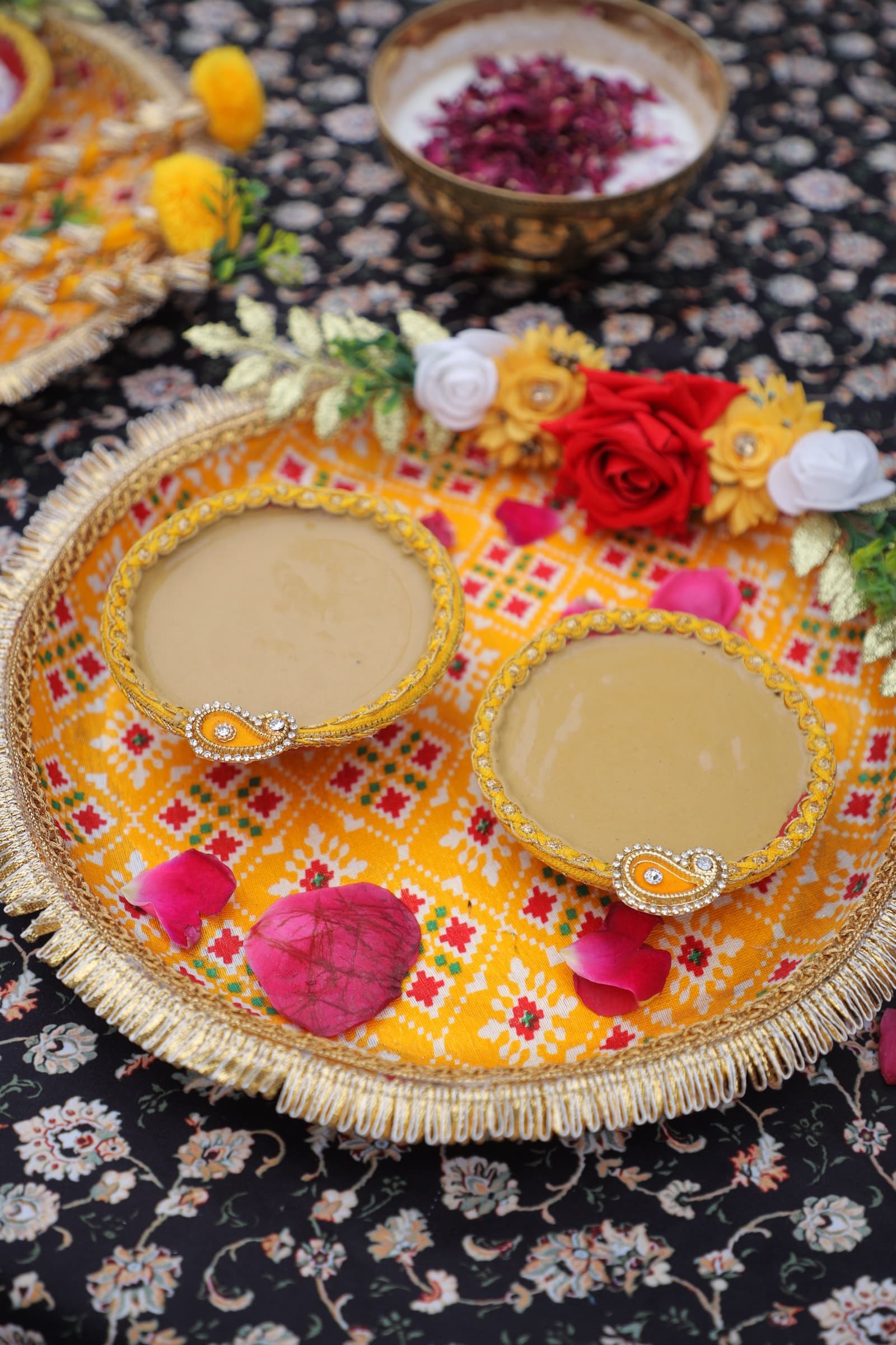 Two clay diyas of haldi paste edged in gold lace