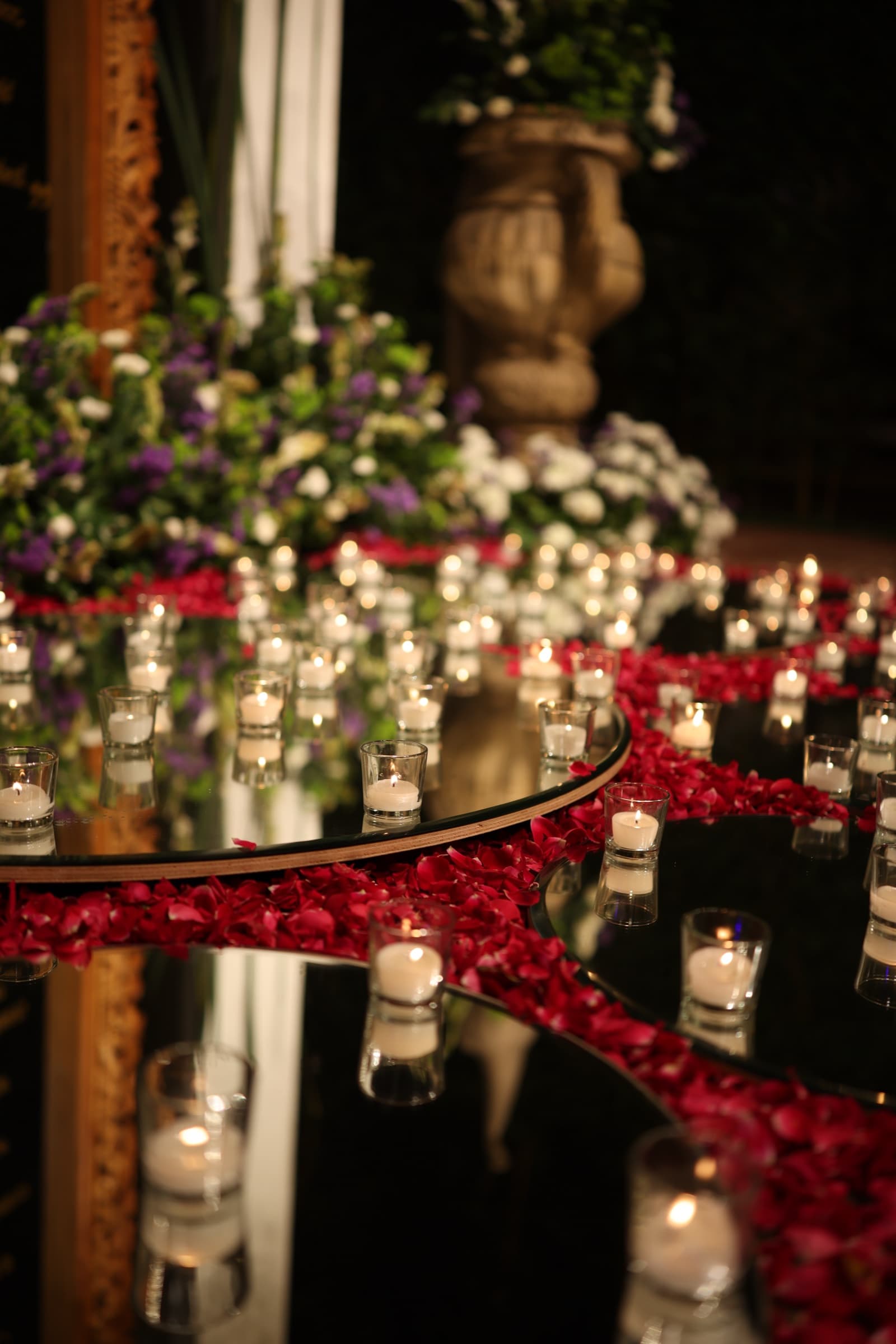 Candles glowing on mirrored trays scattered with rose petals