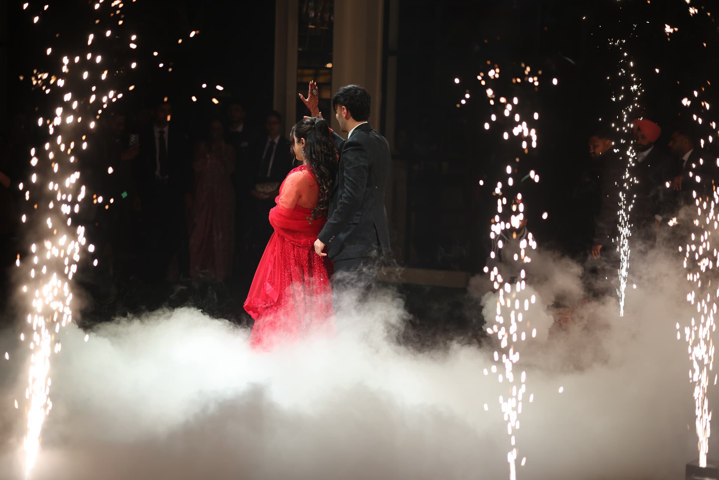 The couple's choreographed entrance through cold-spark fountains and fog